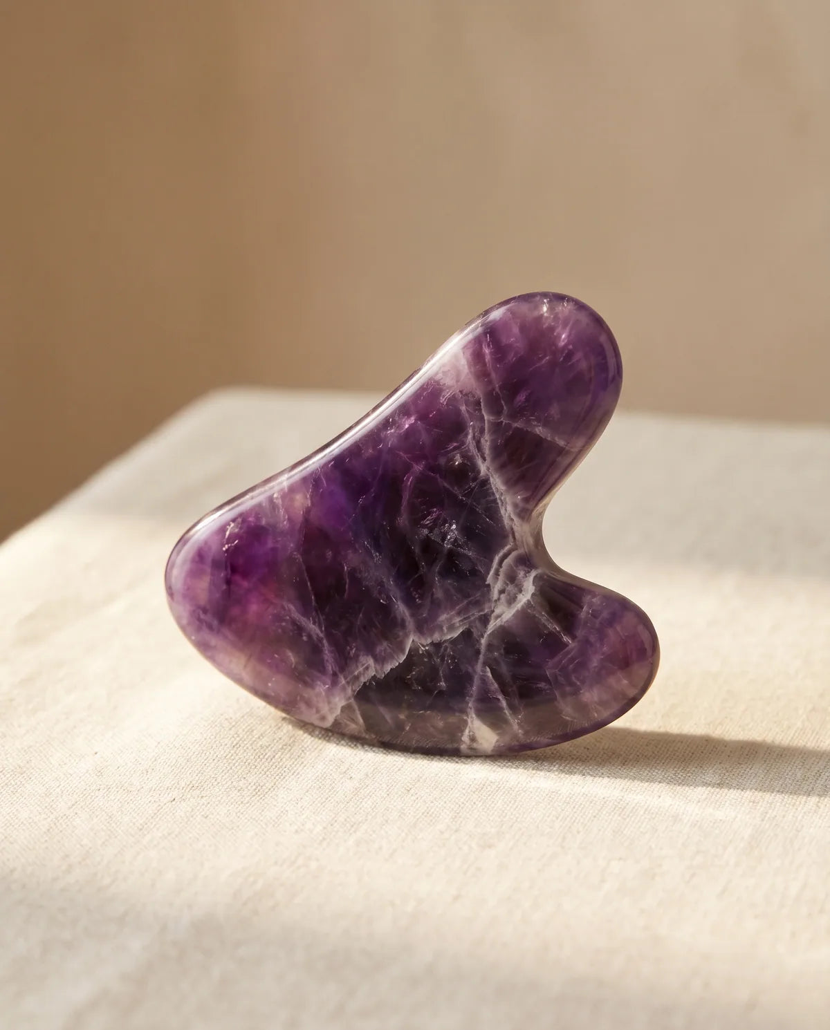 BY RITUEL amethyst gua sha tool on marble surface